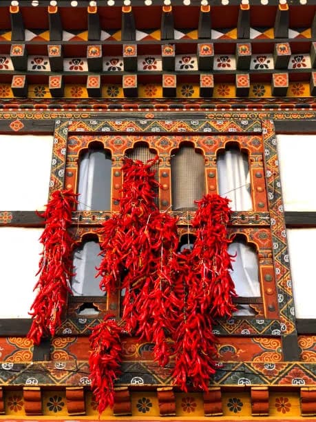 Red chillies hanging beside a painted Bhutanese window