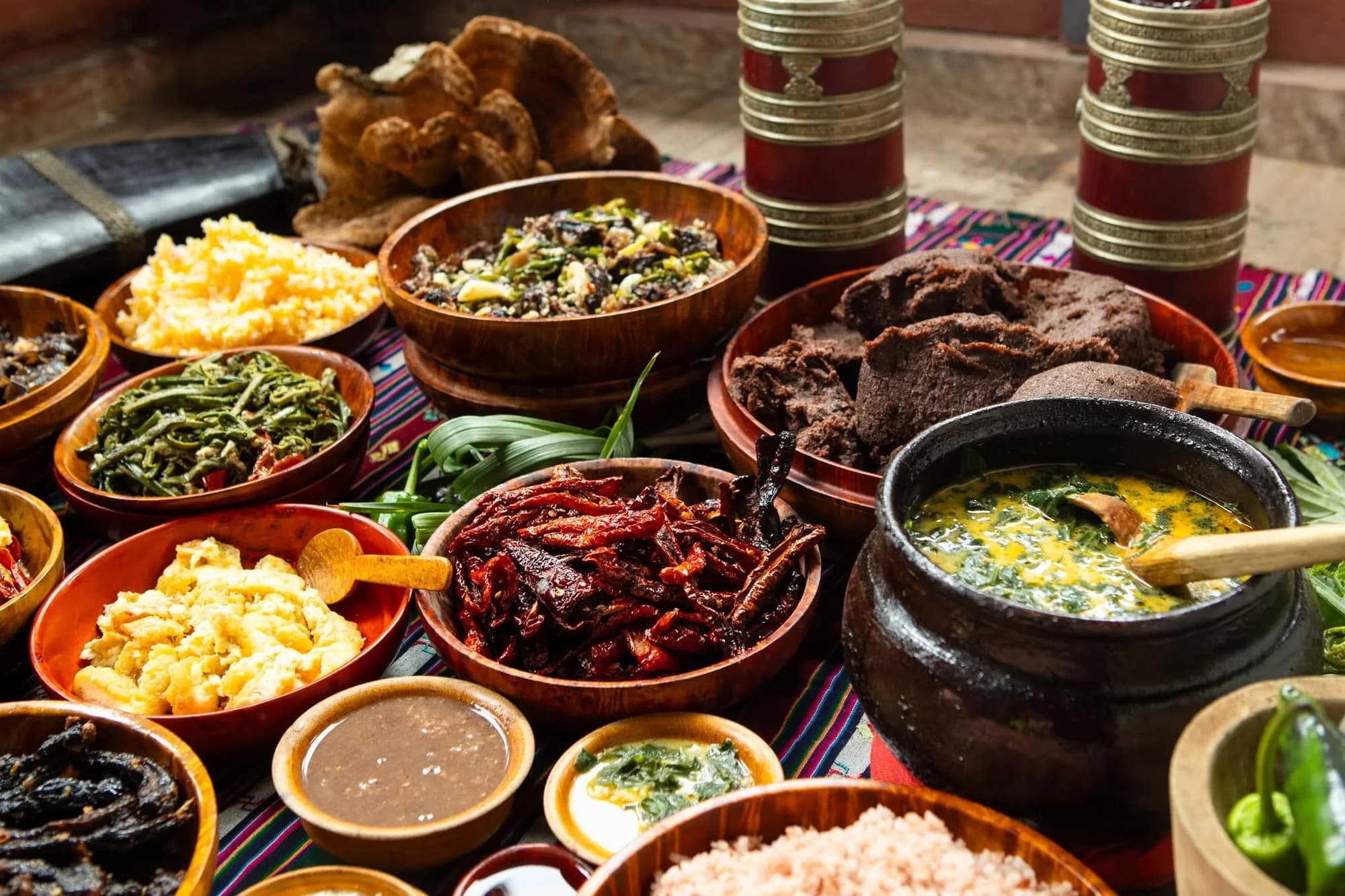 A table of traditional Bhutanese dishes and ingredients in wooden and brass bowls