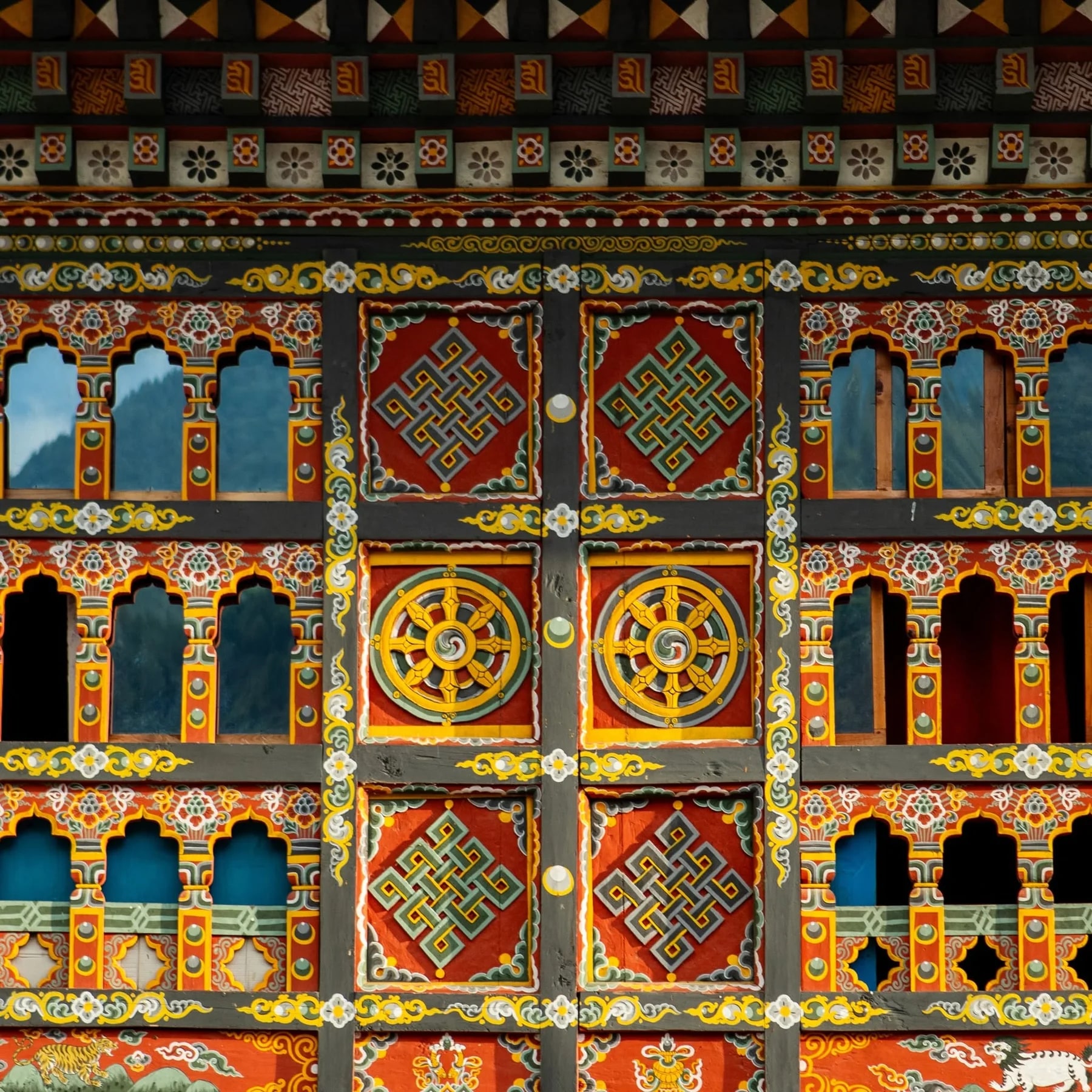 A richly painted traditional Bhutanese building facade with carved windows